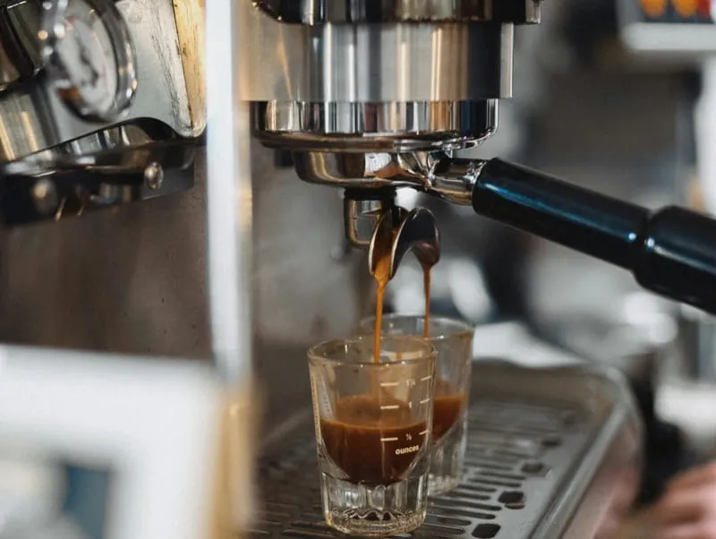 Fresh espresso pulling from portafilter into glass