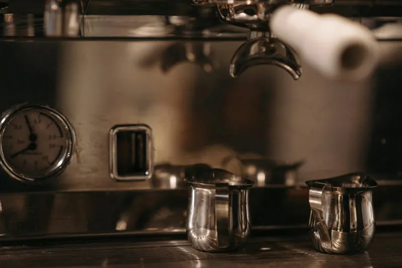 Barista operating professional espresso machine at coffee bar