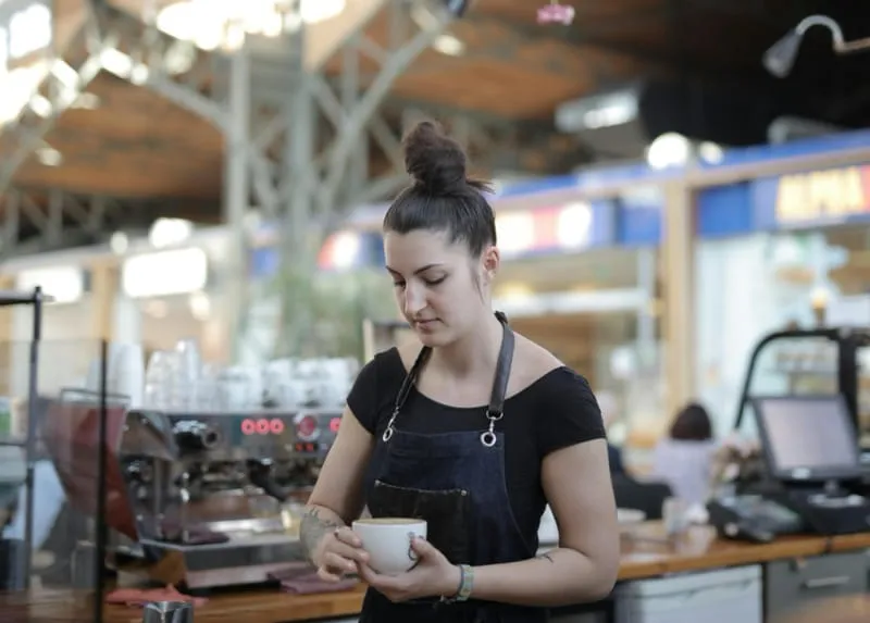 Smiling barista handing coffee to customer at event
